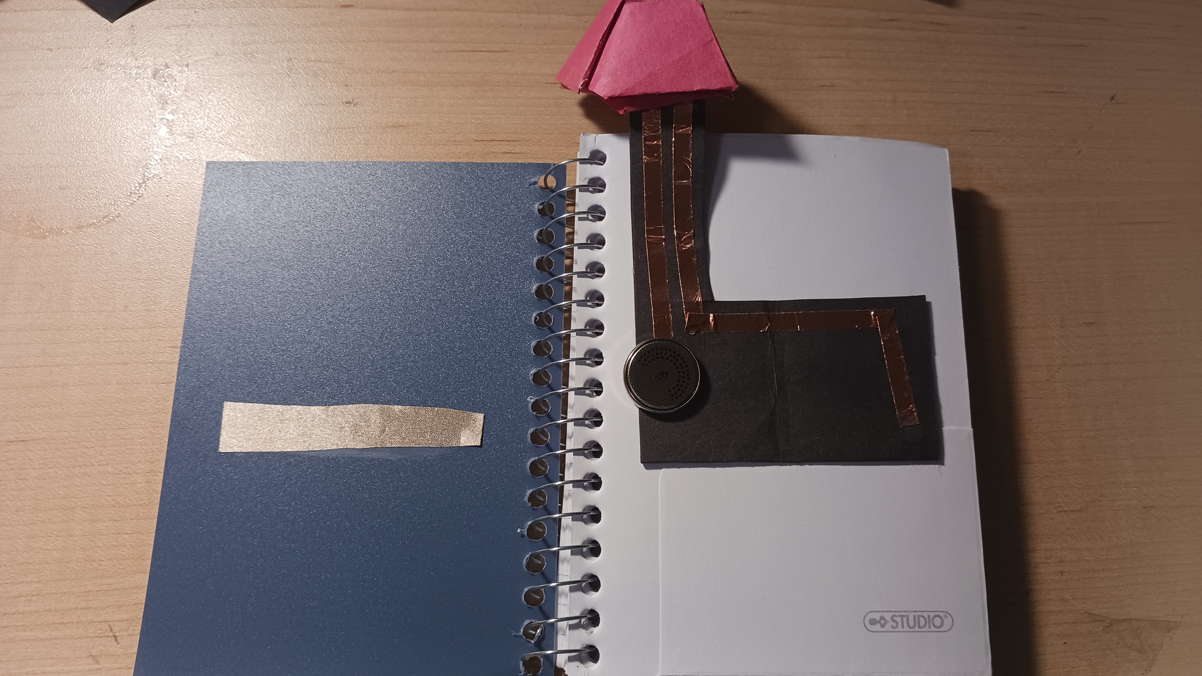 A book light that turns on when the circuit connects to the tape located on another page when the page is flipped